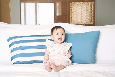 Portrait of cute baby girl on bed at home
