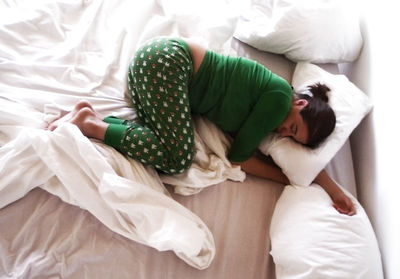 High angle view of young woman sleeping on bed