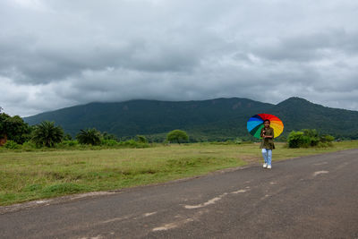 Rear view of people walking on road against sky