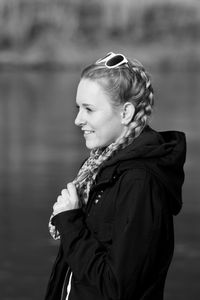 Side view of young smiling woman with braided hair while standing at lakeshore