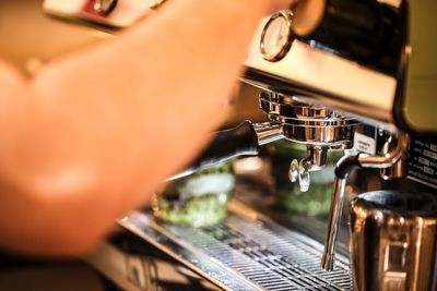 Cropped hand preparing coffee in cafe