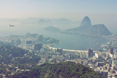 Aerial view of city by sea against sky