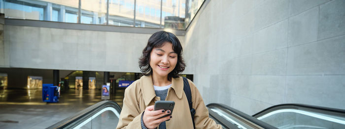 Portrait of young woman standing in city