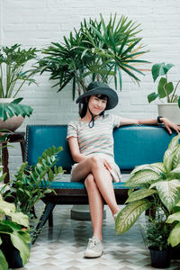 Portrait of woman sitting on chair against plants