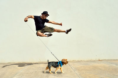 Man with dog jumping by wall