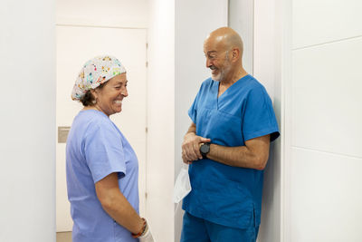 Happy dentist talking with nurse in corridor