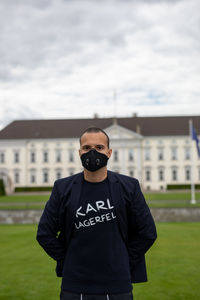 Portrait of man wearing mask standing against building