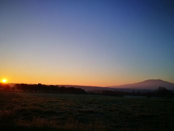 Scenic view of field against clear sky during sunset