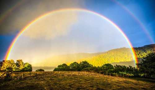 Scenic view of rainbow over landscape against sky