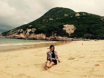 Full length of young woman sitting on beach