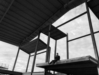 Low angle view of man on built structure against sky