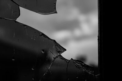 Close-up of wet window against sky