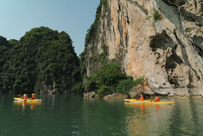 People kayaking against rocky cliff