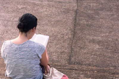 Woman reading book while sitting on steps
