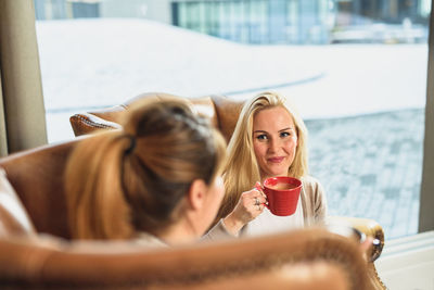 Adult female drinking coffee with friend