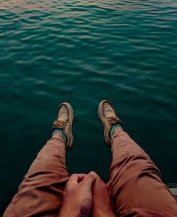 Low section of man sitting on pier over sea