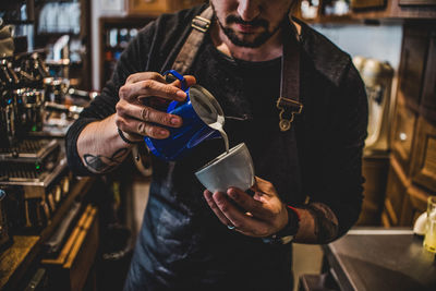 Midsection of man making coffee in cafe