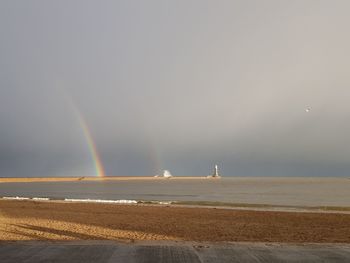 Scenic view of sea against rainbow in sky