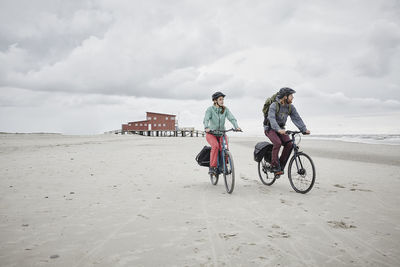 Germany, schleswig-holstein, st peter-ording, couple riding bicycle on the beach