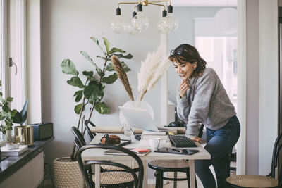 Smiling woman talking on the phone working at home