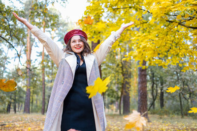 Portrait of young woman standing against tree