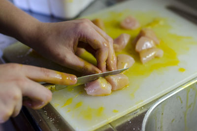 Close-up of woman slicing meat on cutting board