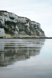 Reflection of rocks in lake against sky