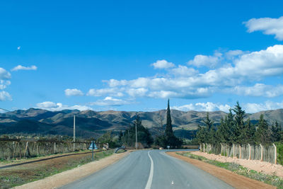 Empty road along landscape and mountains against sky