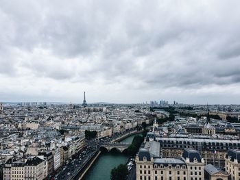 Cityscape with eiffel tower in background against cloudy sky