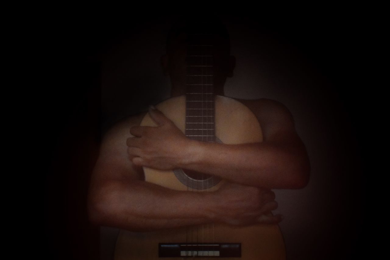 MIDSECTION OF MAN HOLDING GUITAR