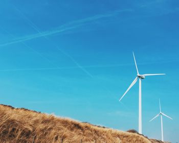 Wind turbines on field against sky