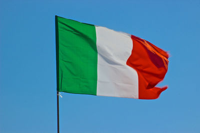 Low angle view of flag against blue sky