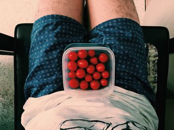 Midsection of man sitting with food in container