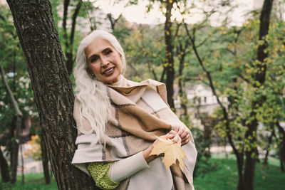 Portrait of a smiling young woman against tree trunk