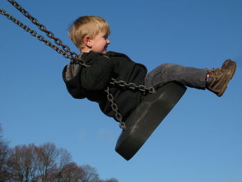 Young boy swings on swing in  playground