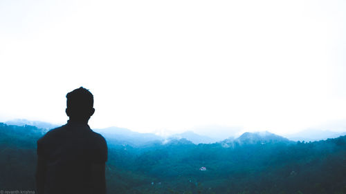 Rear view of silhouette man against mountains against clear sky
