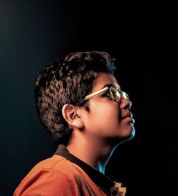 Portrait of young man looking away against black background