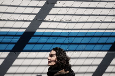 Side view of young woman against wall