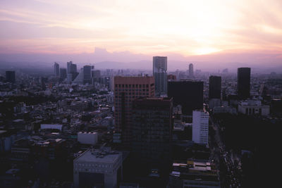 Aerial view of buildings in city against sky during sunset