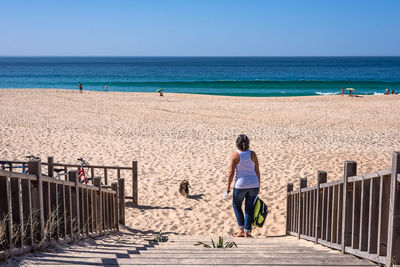Rear view of man standing on beach against clear sky
