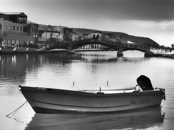 Boat moored on river by bridge against sky