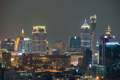 Illuminated buildings in city against sky at night