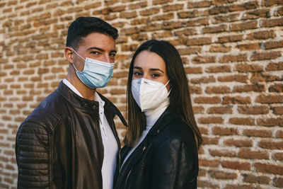 Portrait of friends wearing mask against wall