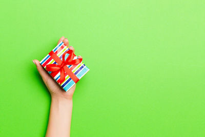 Cropped hand holding christmas present on colored background