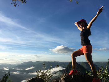 Low angle view of woman with arms outstretched against sky