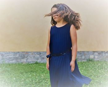 Young woman standing against wall