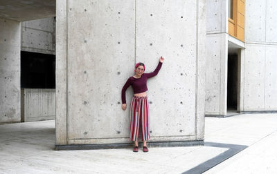 Full length of woman standing against concrete wall