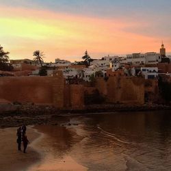 Scenic view of river by town against sky during sunset