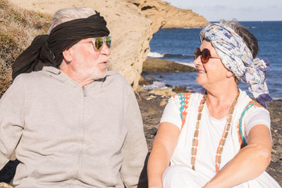 Couple in sunglasses sitting at beach