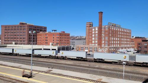 Railroad tracks amidst buildings in city against clear blue sky